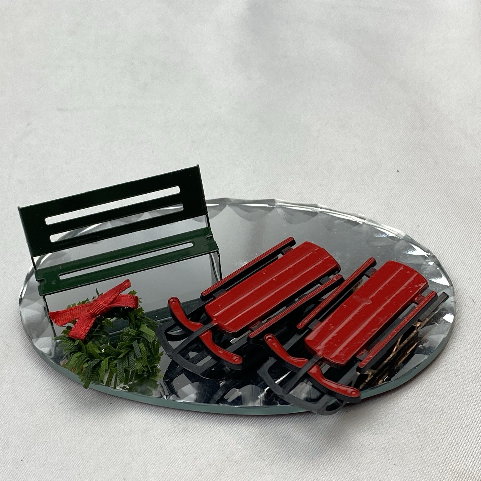 Christmas Village Sleds, Park Bench, Wreath With A Bow, And Mirror Brand Unknown