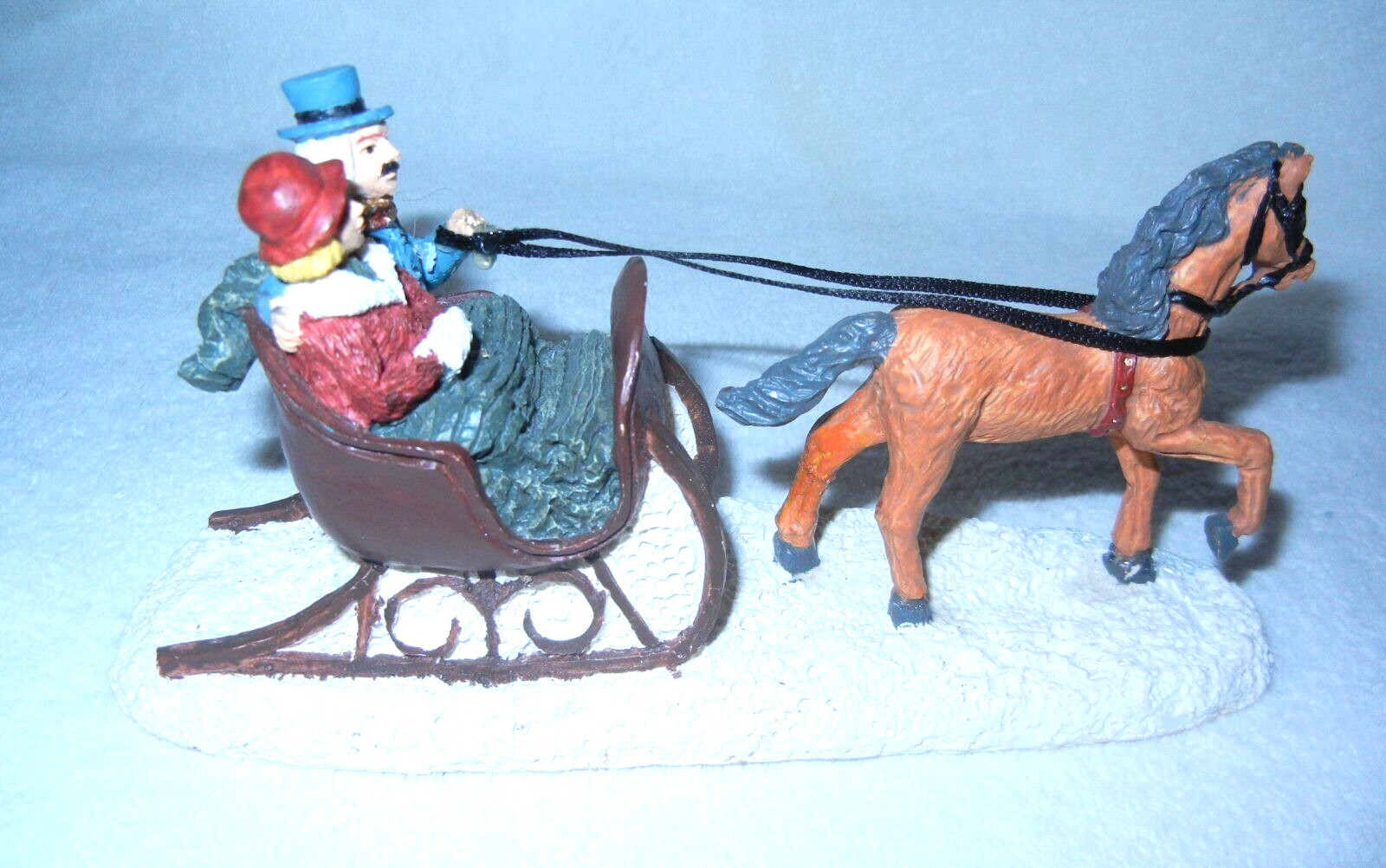 A COUPLE IN A BROWN SLEIGH PULLED BY LIGHT-BROWN HORSE VILLAGE ACCESSORY 6 1/2″L